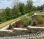 A professionally engineered multi-tiered limestone retaining wall stabilizing a steep backyard slope in Clarence, NY, featuring native deep-rooted plantings and protective coir matting to prevent soil erosion.